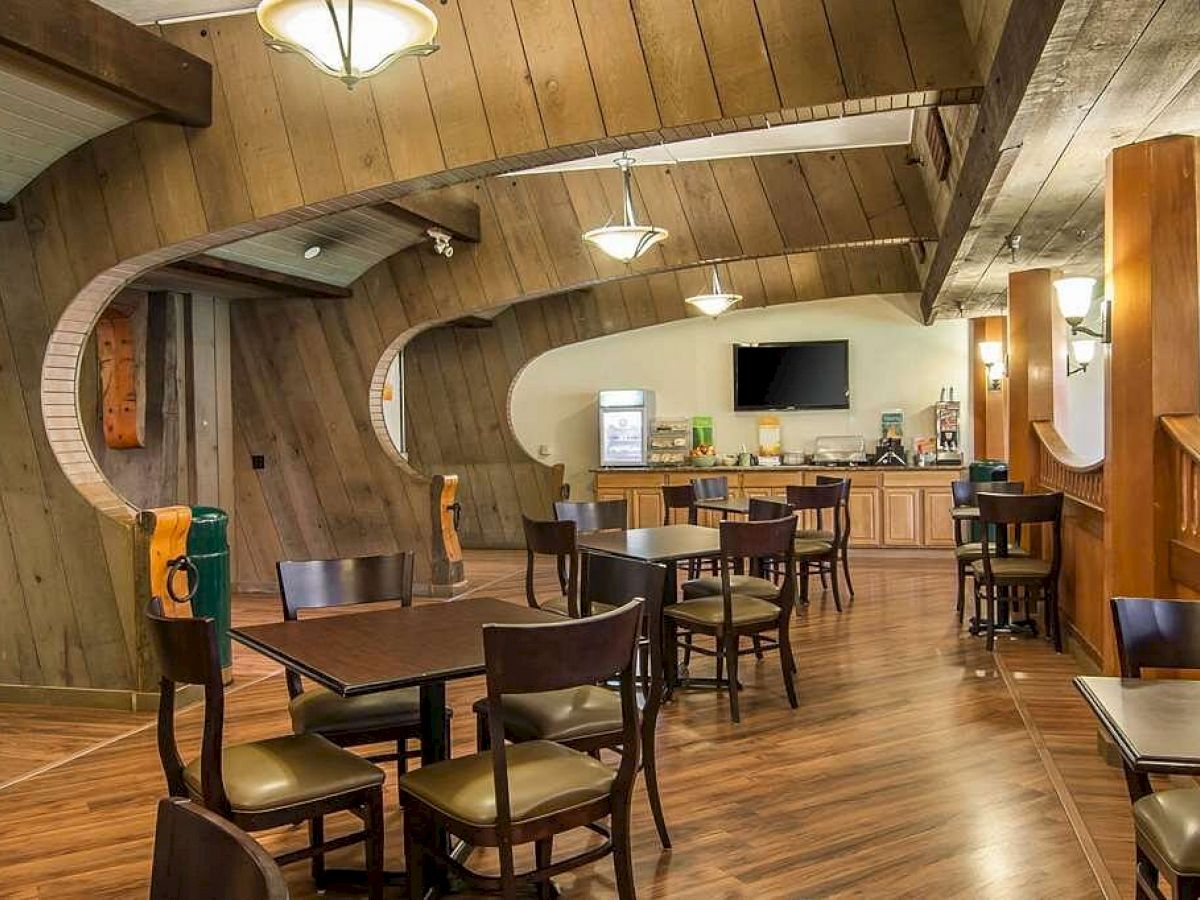 This image shows a modern, wooden-themed restaurant interior with tables, chairs, and a small service counter in the background.