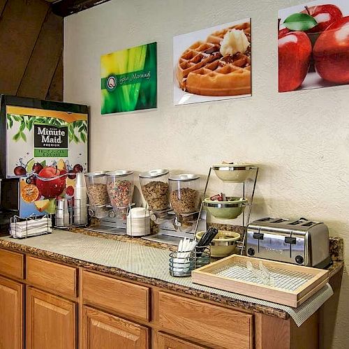 The image shows a breakfast buffet with cereal dispensers, a waffle maker, a toaster, a drink machine, and various utensils on a countertop.